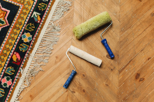 two paint rollers on the ground next to a rug